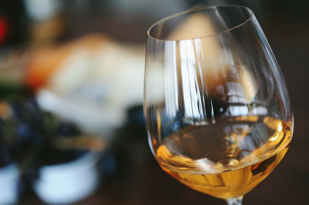 White wine in a glass and blurred colorful fond behind 