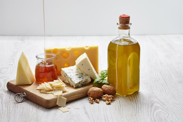 Assorted cheeses, olive oil bottle, honey and nuts on a wooden board